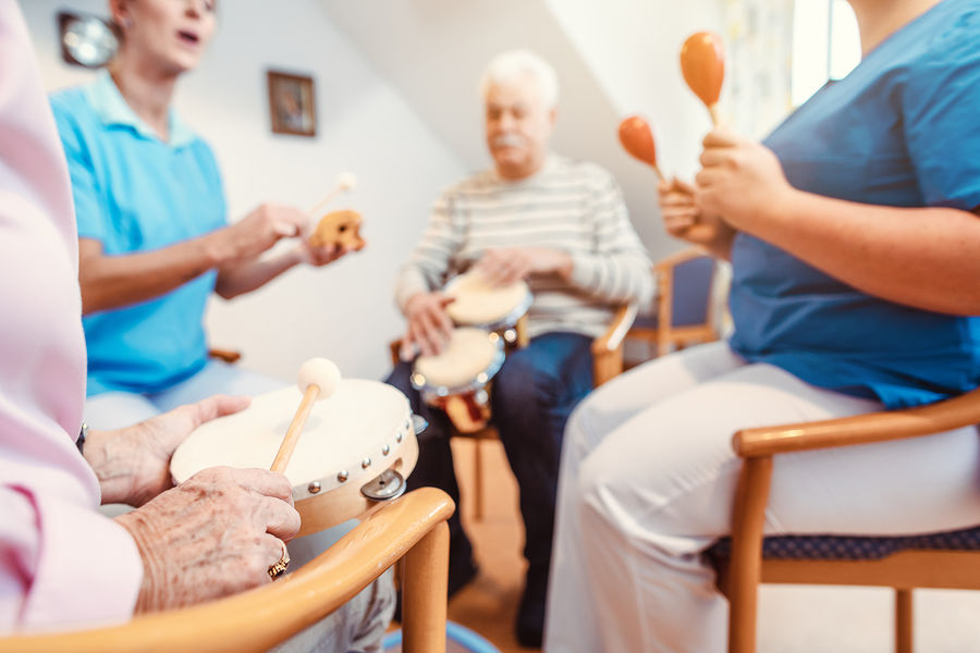 Seniors in nursing home making music with rhythm instruments as musical therapy